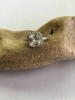 Front view of ring showing cushion-cut clear crystal solitaire and surrounding smaller stones on band