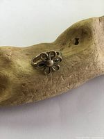 Front and angle view of the sterling silver flower ring on a wood textured background, showing the flower design and tarnished surface.