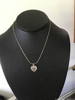 Full view of the necklace with heart charm pendant displayed on black bust