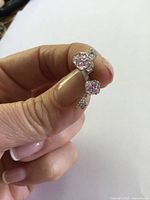 Close-up of the lock and key sterling silver stud earrings showing the pink topaz stones and design details held between fingers.