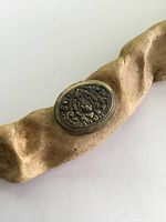 Oval Tibetan silver snuff/pill box showing repousse decoration on top with floral and scroll design.