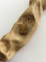 Rectangular carved Tiger's Eye cameo resting on textured wood, showing profile design and polished surface.