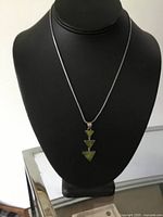 Necklace displayed on black bust showing thin 17-inch chain with triangular drop pendant with green abalone shells facing forward.