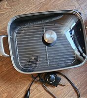 Top view of the Breville electric fry and sauté pan, showing the stainless steel rack inside and the clear glass lid with stainless steel knob placed over the pan.