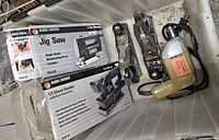 Photo of the Black & Decker MT Series jig saw box, 1/3 sheet sander box, two metal hand planes, and the Black & Decker corded drill inside a plastic container