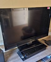 Full frontal view of the LG 31-inch television on a table with the remote placed in front beneath it. The screen is off and reflecting the room.