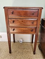 Front view of a wooden occasional side table with three drawers and round wooden knobs.