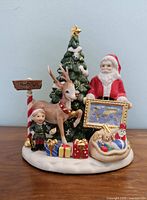 Full view of the Royal Doulton Santa's World Map figurine showing Santa, reindeer, elf, Christmas tree, presents and North Pole signpost on a white snow base.