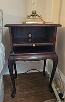 Front view of the vintage solid wood occasional table showing open compartment with brass knob and cabriole legs.