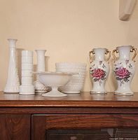 Full view of the collection showing five white milk glass pieces with textured patterns and two matching white china vases with gold trim and red rose decorations