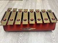 Full view of the Tudor xylophone showing nine brass keys on a red base with the Tudor brand logo.