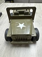 Front view of the olive green Mighty Mo jeep toy with white star on hood, showing molded grille and black wheels on table surface.