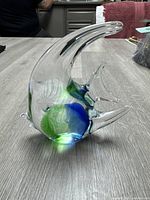 Side angle of clear glass angel fish paperweight showing its smooth curved shape and colored accents.
