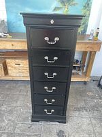 Front view of the black wooden tall lingerie storage cabinet showing seven drawers with metal handles and key lock on the top drawer.