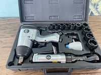 Open black plastic carrying case holding two pneumatic ratchets, 10 sockets, an oiler bottle, and a small black box in compartments