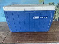 Blue Coleman PolyLite 48 cooler with white lid, front side view with logo visible.