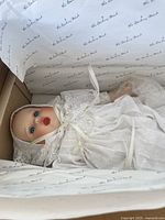 Danbury Mint Gerber baby doll dressed in white lace gown and bonnet inside original box with branded tissue paper.