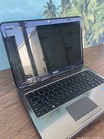 Front angled view of Dell Inspiron laptop opened showing screen, keyboard, and touchpad