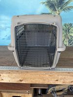 Front view of the plastic animal kennel carrier featuring a black metal wire door and ventilation slots on the sides.