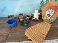 Overall view of the lot items on a wooden surface including the clown stepstool, ceramics, small figurines, and decorative pieces.