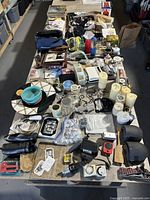 Large assortment of items on a table including kitchen bowls, glass jars, candles, and assorted household goods.