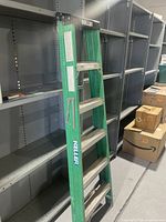 Full side view of the 6 foot green Keller fiberglass ladder showing metal steps and safety label.