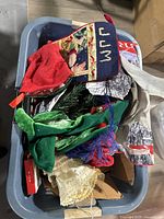 Laundry basket filled with Christmas stockings, elf hats, tree skirt, and other fabric holiday decorations.