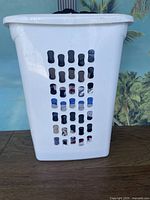 White plastic laundry basket with multiple ventilation holes, visible cracks and some wear marks.