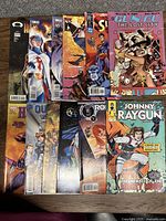 Photo showing front covers of 12 comic books arranged side by side, titles and artwork clearly visible.