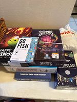 Photo of stack of games including Happy Little Dinosaurs, Skipbo, Go Fish, Chronology, and The Best Friend Game.