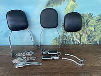 Various motorcycle accessories including three padded backrests, foot pegs, levers, and Honda Valkyrie badges