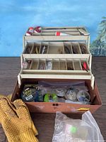 Plano tackle box with fishing accessories inside compartments, includes lures, tools, and bobbers