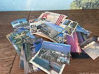 Wide shot of assorted unused postcards spread on wooden table, showing various scenic images mostly from Santa Barbara area.