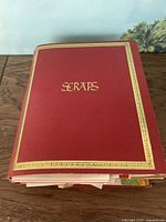 Red hardcover scrapbook labeled 'SCRAPS' showing gold decorative border and title on cover