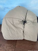 Rolled up beige sleeping bag showing fabric and drawstring closure.