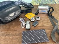 Full lot overview showing Sony Handycam with wrist strap, carrying case, two extra lenses, extra battery, remote control, audio/video cables, and lens cleaning tissue