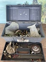 Open grey Stack-On toolbox filled with various plumbing supplies including fittings and washers inside plastic bags and loose in the box.