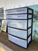 Full view of the Sterilite storage tower showing black frame and five semi-transparent white drawers of varying sizes.