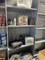 Shelf with country music LP records, books, black MosaiK toolbox, decorative tin container, and glass mason jars