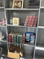Full shelf with Bibles, books, LP record, electronic box, organizer, and framed picture.