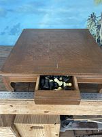 Full top view of the wooden tabletop chess set showing chessboard integrated into the chest and partly open drawer with chess pieces visible inside.