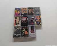 Photo showing 11 used cassette tapes with visible album artwork from classic rock bands.