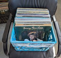 Blue crate filled with dozens of vinyl records, front record is Barry Manilow Greatest Hits Vol II