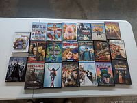 Top-down photo of 20 assorted DVD movie cases arranged in rows on a white surface.