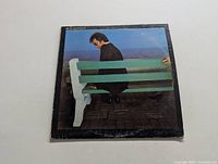Front cover of Boz Scaggs Silk Degrees LP showing a man sitting on a green bench near water, edges of cover show wear.