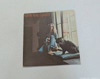 Front cover of Carole King Tapestry vinyl LP featuring Carole King with a cat by a window.
