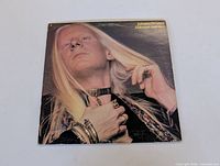 Front cover of the Johnny Winter "Still Alive and Well" LP showing a close-up image of Johnny Winter wearing jewelry and a serious expression.