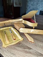 Photo showing the full set including grand piano jewel box open with red velvet lining, tray with manicure tools, brush and comb all in ivory celluloid.