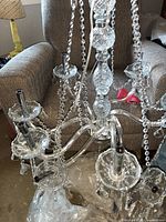 Top view of large crystal chandelier showing multiple glass arms with candle-style sockets and hanging crystal beads.