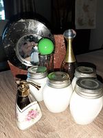 Photo showing round heavy marble frame mirror, vintage perfume bottles, and milk glass jars grouped together